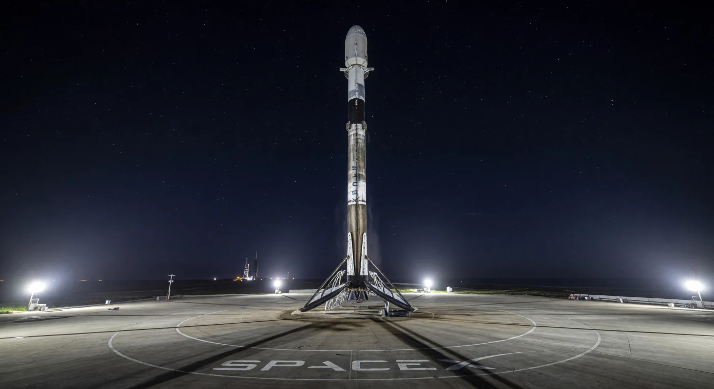 Il primo stadio del Falcon 9 di SpaceX si erge maestoso sulla Landing Zone 1 di Cape Canaveral nel dicembre 2015, segnando il primo atterraggio verticale di successo di un razzo di classe orbitale. La struttura, alta 70 metri e annerita dalla fuliggine del rientro atmosferico, poggia saldamente su quattro gambe in fibra di carbonio sotto le luci industriali della Florida. Questo traguardo storico ha inaugurato l'era della missilistica riutilizzabile, trasformando radicalmente l'economia dell'esplorazione spaziale e rendendo il cosmo più accessibile all'umanità.